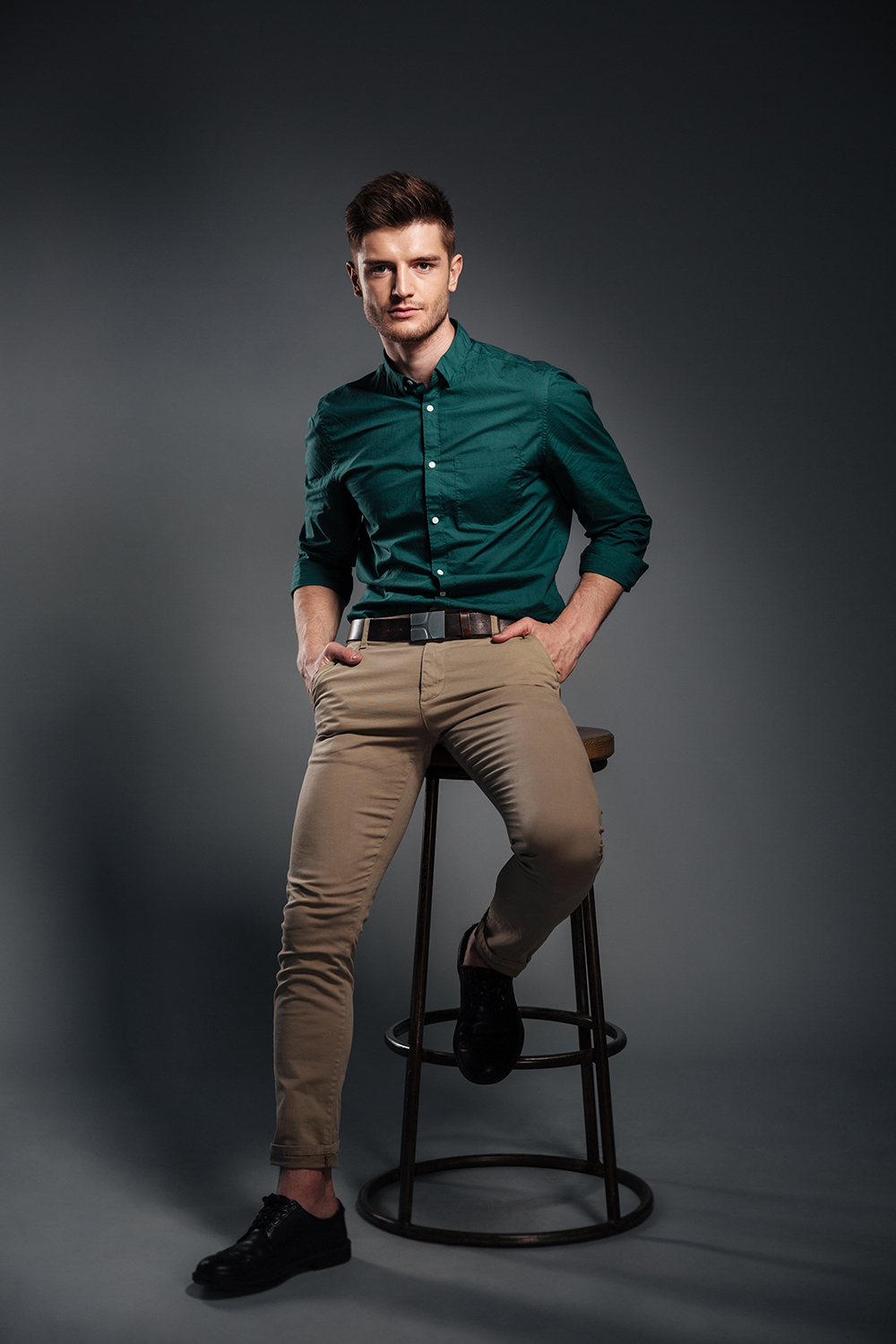 handsome young man sitting isolated over grey background